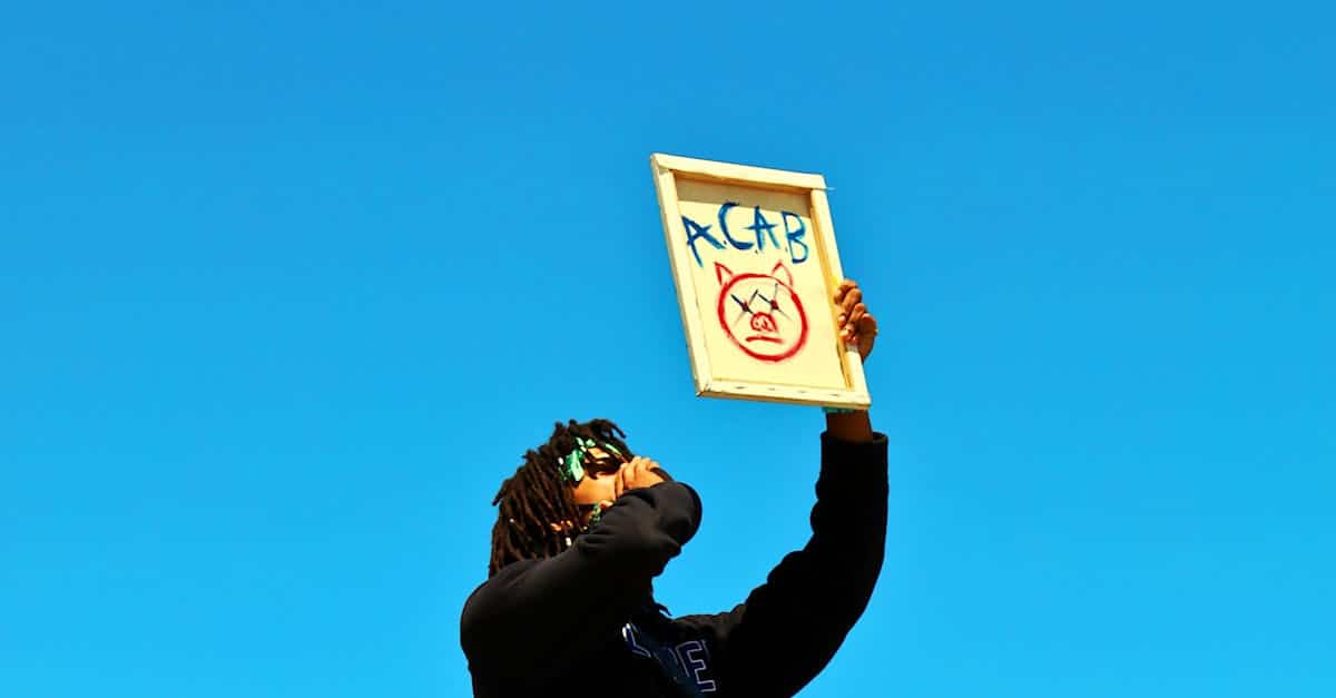 a protester raises a sign during a demonstration in los angeles under a clear blue sky